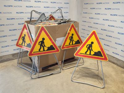 three construction signs on a stand in front of a wall