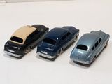 four toy cars are lined up in a row on a white surface