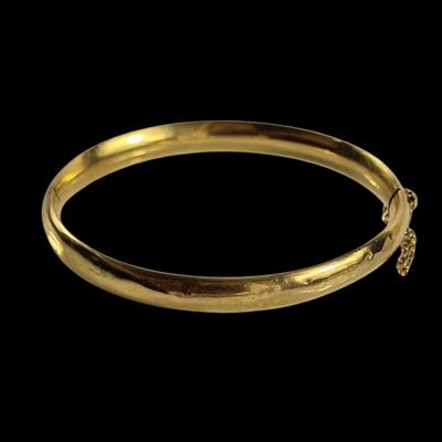 gros plan d'un bracelet en or sur fond noir