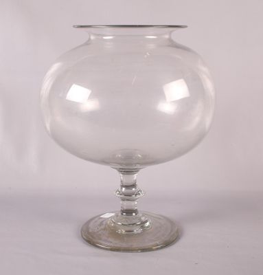 un vase en verre transparent avec un socle transparent posé sur une table