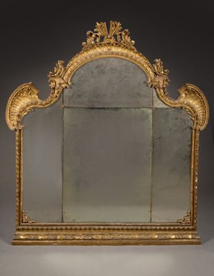 an ornately carved mirror with a gold frame on a grey background