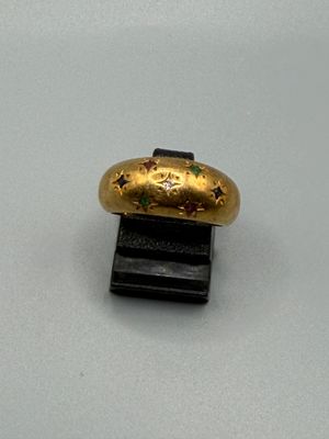une bague en or posée sur un socle noir, sur une surface blanche