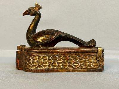 figurine en laiton représentant un paon perché sur un livre posé sur une table
