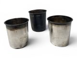 three metal cups are lined up in a row on a white surface