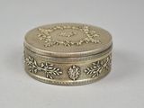 an antique silver box with a floral design on the lid