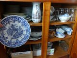une personne tenant une assiette bleue et blanche devant une armoire