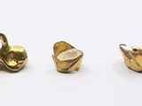 three pieces of gold colored metal on a white surface