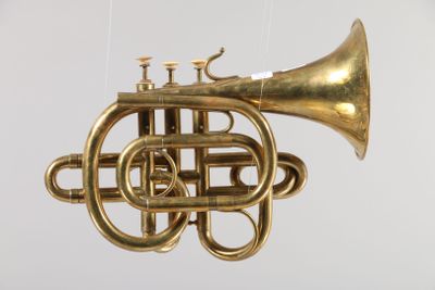 un instrument à vent en laiton suspendu à une ficelle sur un fond blanc