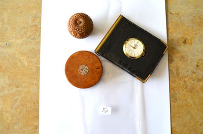 une petite boîte sur laquelle est posée une montre, à côté d'un petit objet marron