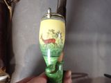 a person holding a green and yellow vase with a deer on it