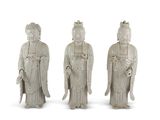 trois statues blanches représentant des personnes d'origine asiatique, placées côte à côte sur une surface blanche