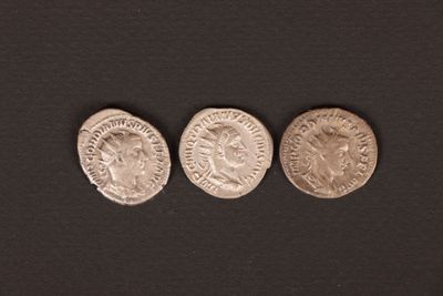 three ancient roman coins on a black background