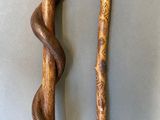 pair of wooden walking sticks with a snake wrapped around them