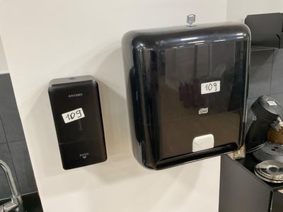 a black paper towel dispenser on the wall next to a sink