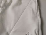 the bottom of a pair of white pants with a logo on it