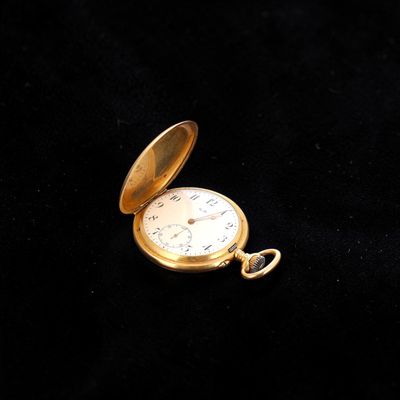 an old gold pocket watch sitting on a black surface