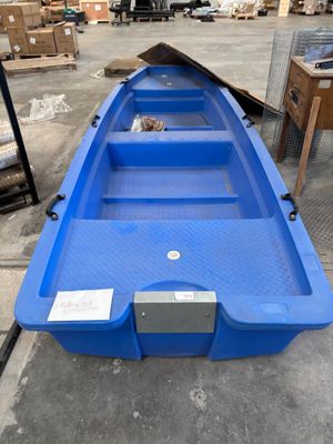 an empty blue boat sitting on top of a floor in a warehouse