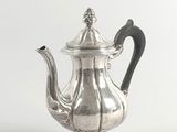 an antique silver teapot with a black handle on a white background