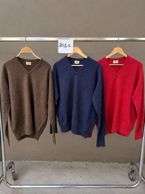 trois pulls suspendus à un portant dans un magasin de vêtements