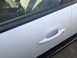 a white car with a door handle on the side of the road
