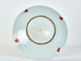 a blue plate with red flowers on it on a white surface