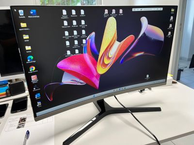 a computer monitor sitting on top of a desk next to a cell phone