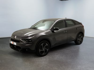 Une voiture grise est garée dans une pièce aux murs blancs.