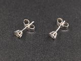 a pair of silver earrings on a black surface