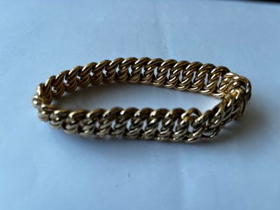 gros plan d'un bracelet en chaîne en or sur une surface blanche