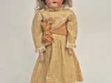 an old fashioned doll with blonde hair and a yellow dress