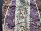 un vieux sac à main violet et blanc orné de fleurs, posé sur une table