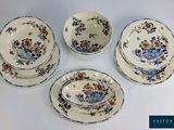 four pieces of blue and orange floral dinnerware on a white table
