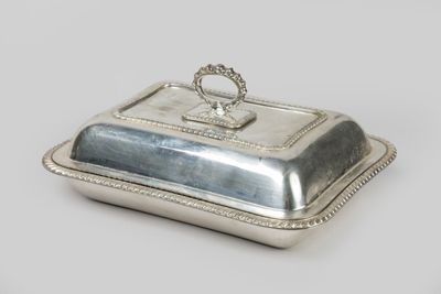 an antique silver plate covered with a handle and a ring on top