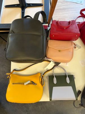 several different colored handbags are sitting on a table next to each other