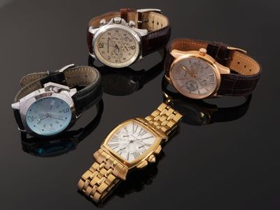 three watches are sitting on a black surface with a black background