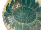 a green and white vase sitting on a black stand