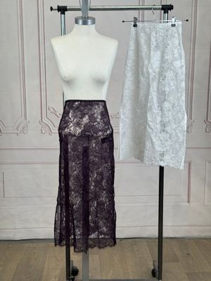 two skirts on a mannequin stand in front of a white wall