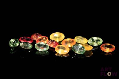 un gros plan sur un assortiment de pierres précieuses de différentes couleurs posées sur une surface noire