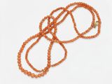 un collier de perles orange muni d'un fermoir doré, sur fond blanc