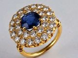 gros plan d'une bague avec une pierre bleue entourée de diamants blancs