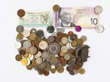 un tas de pièces et un billet de banque posés sur une surface blanche