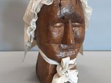 une tête en bois surmontée d'un foulard blanc