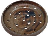 a rusted metal tray with holes in it
