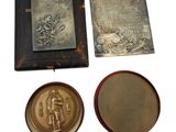 three metal objects including a plaque, a book and a mirror