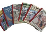 several children ' s books are lined up on a white surface