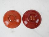 pair of red bowls with chinese writing on them sitting on a table