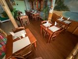 des tables et des chaises dans un restaurant où est accrochée une peinture au mur