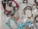 many different necklaces and bracelets laid out on a table