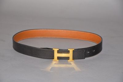 a close up of a black and orange belt with a gold h buckle