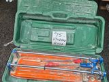 une mallette verte posée par terre, contenant des outils